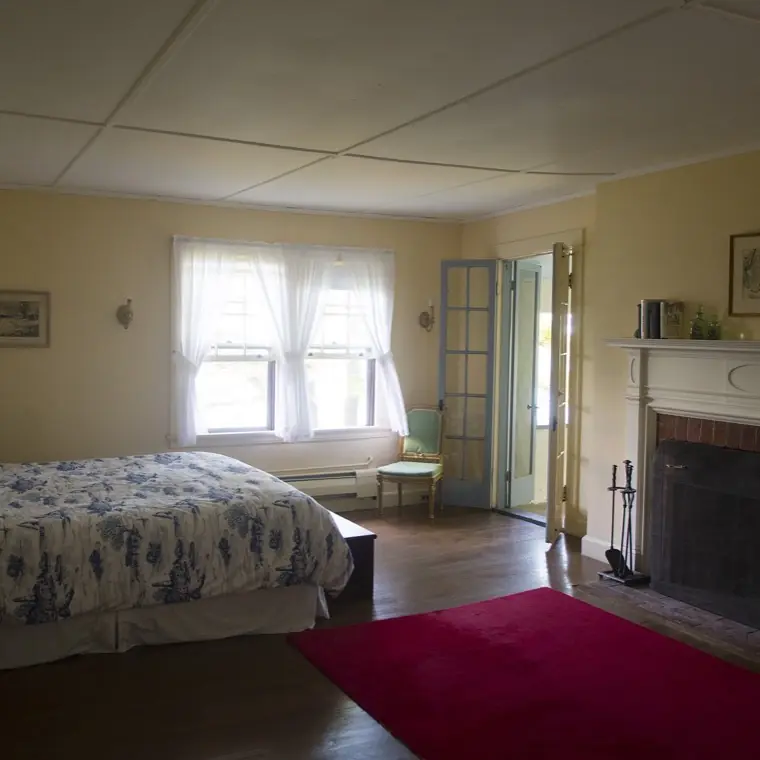 A bedroom with period furnishings and windows open to the sea air